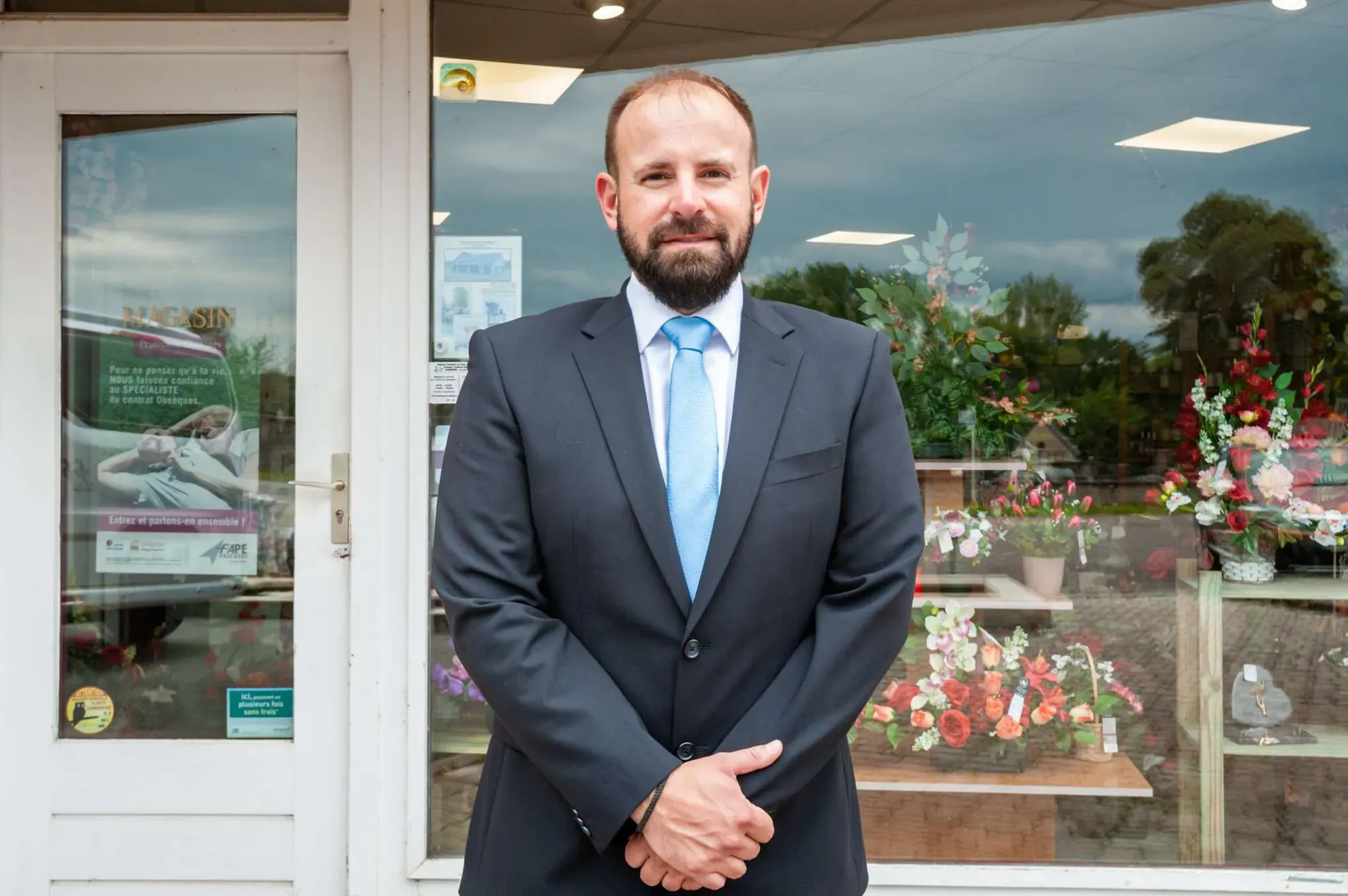 Portrait du responsable des pompes funèbres devant la vitrine du magasin.