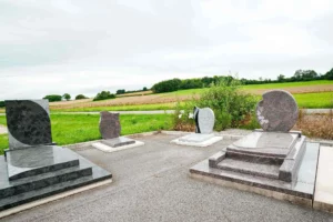 Exposition extérieure de monuments funéraires en granit face à la campagne.